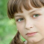 Cute preteen schoolgirl is making make-up during lesson at schoo ...