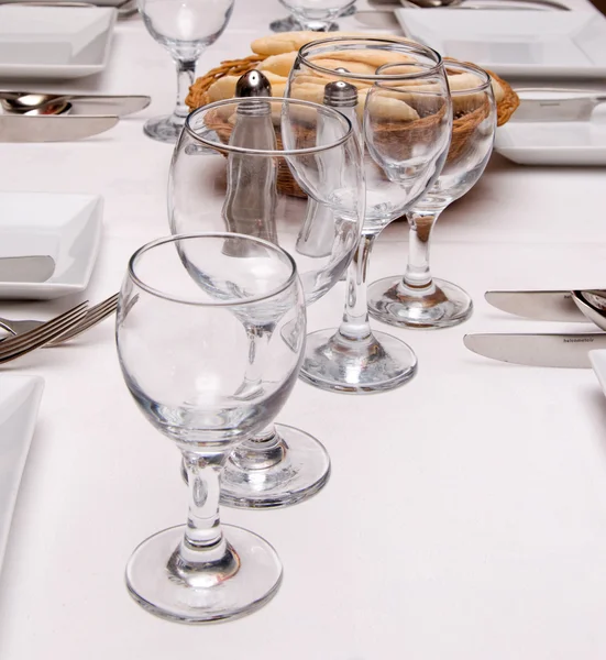 Tableware, glass tumblers, cutlery, bread on a white tablecloth
