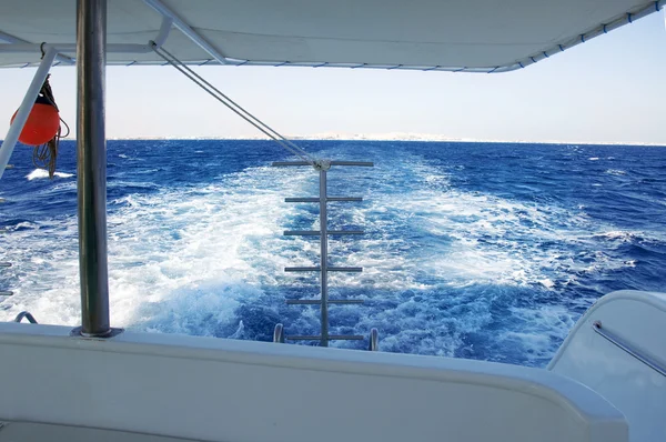 Ярко-голубая морская вода, следы гребных винтов яхты — стоковое фото