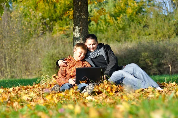 stock image Happy family with notebook under tree in autumn