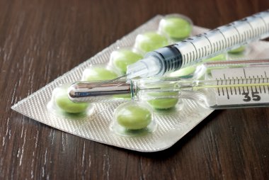 Syringe, pills and a thermometer on the black table clipart