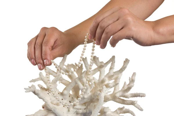 A pearl necklace in her hands against the backdrop of coral — Stock Photo, Image
