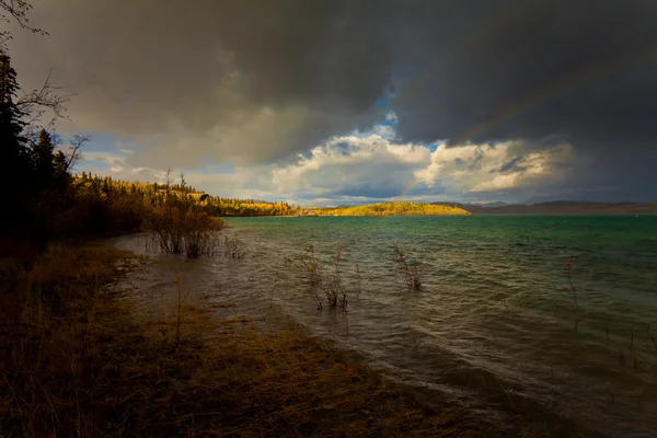 Arc-en-ciel et nuages sombres sur un grand lac — Photo