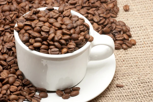 White mug on coffee beans and sacking — Stock Photo, Image