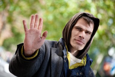 Young Homeless Men with hand outstretched, warding off any unwelcome situations. clipart