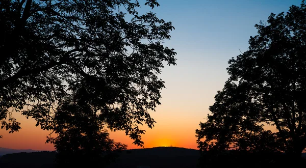 Trauriger Sonnenuntergang mit Sonne und Silhouette von Bäumen und Bergen — Stockfoto
