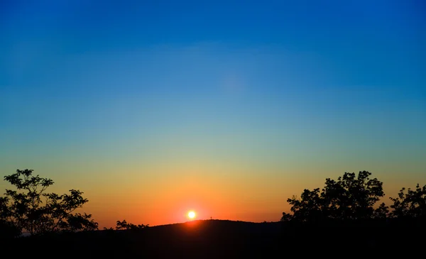 Wounderful ηλιοβασίλεμα με τον ήλιο και siluet δέντρα και βουνά — Φωτογραφία Αρχείου