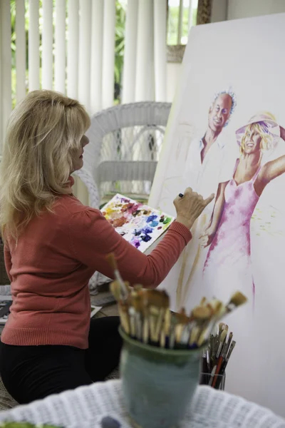 在画布上绘画她五十多岁的艺术家 — 图库照片