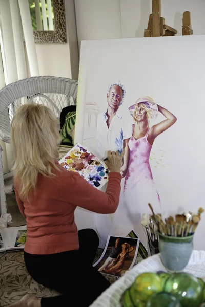 在画布上绘画她五十多岁的艺术家 — 图库照片