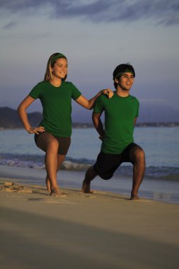 genç bir çift yoga, uzanır ve meditasyon plaj güneş doğarken yapıyor.
