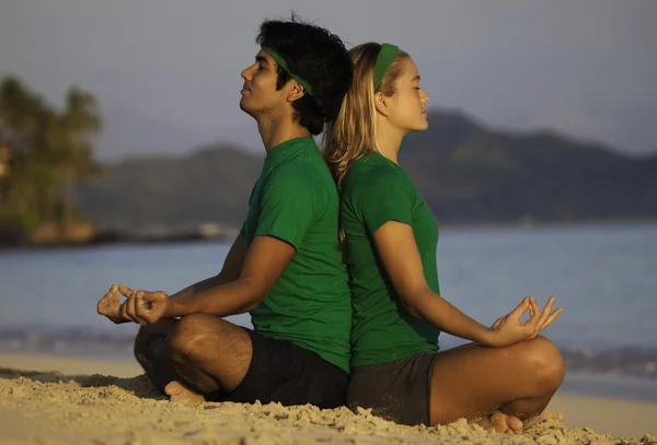 stock image Young couple meditating on the beach at sunrise in hawaii