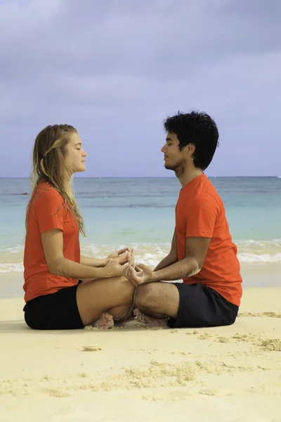 Par mediterar på stranden — Stockfoto