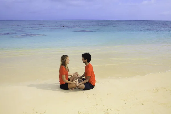 Casal meditando na praia — Fotografia de Stock