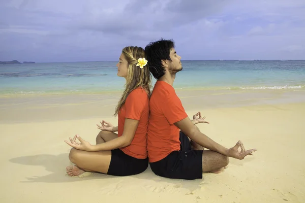 Par mediterar på stranden — Stockfoto