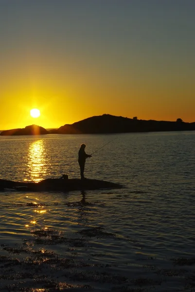 Siluetas de pescador contra la puesta del sol —  Fotos de Stock