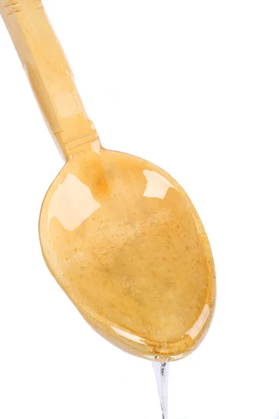 Miele gocciolante lungo il cucchiaio di legno — Foto Stock