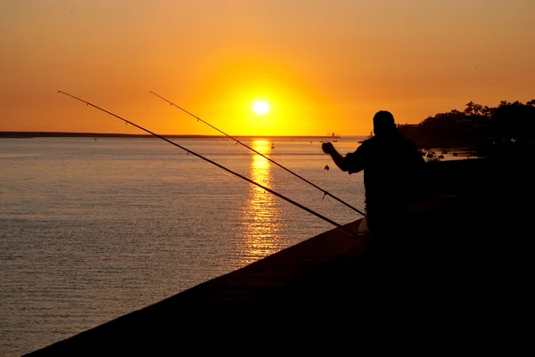 Homem pesca ao pôr-do-sol — Fotografia de Stock