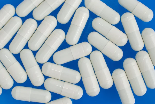 青い背景に白い錠剤のマクロの表示 — ストック写真