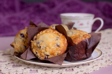 arka planda bir kupa ile bir tabak üzerinde servis blueberry muffins