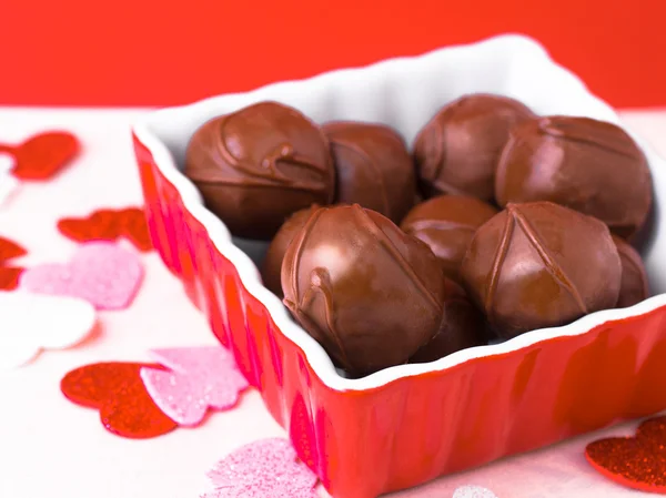 stock image A delicious image of chocolates in a red dish with festive hearts scattered around