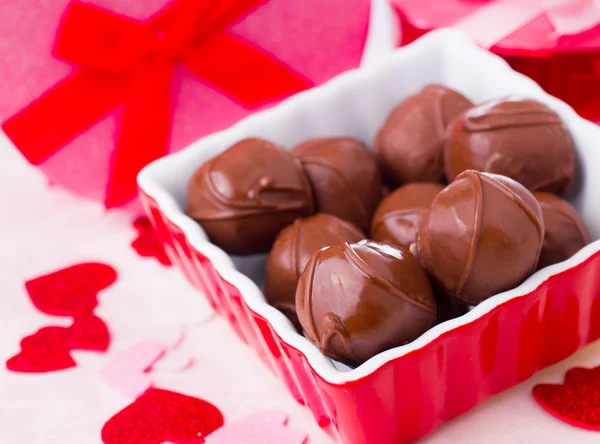 stock image A delicious image of chocolates in a red dish with festive hearts scattered around