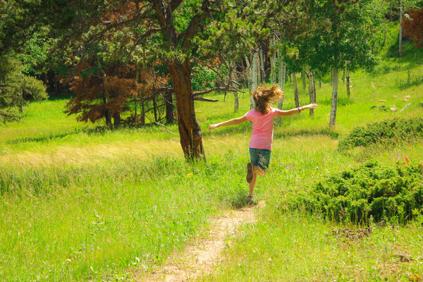 A sweet image of a young girl running carefree in a green field.