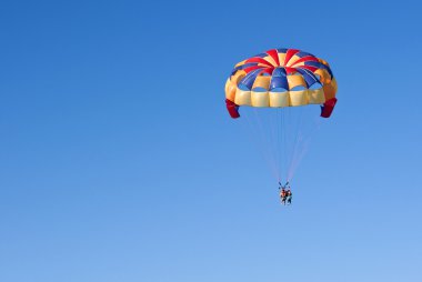 Parasailing under blue sky. clipart