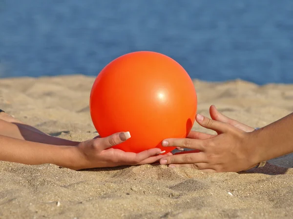 オレンジ色のボール 女性の手のひらビーチの砂を — ストック写真