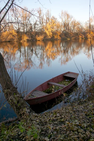 Paesaggio autunnale del fiume con una vecchia barca Foto Stock Royalty Free