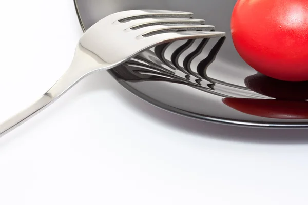 Tomate rojo en un plato negro con tenedor — Foto de Stock