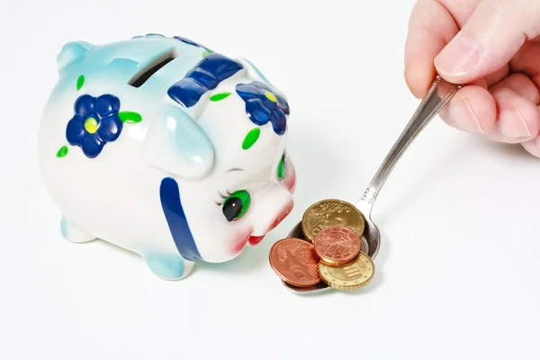पुरुष हाथ एक सूअर बैंक को चम्मच में सिक्के के साथ खिला रहा है — स्टॉक फ़ोटो, इमेज