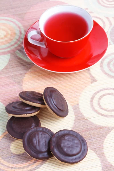 Cup of tea and chocolate iced cookies — Stock Photo, Image
