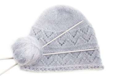 Grey woolen knitted mohair cap with clew and knitting needles clipart