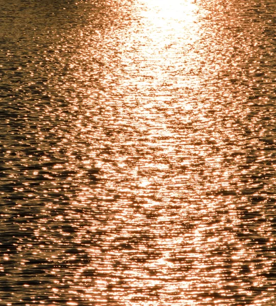 Parches de sol nocturno de luz en la superficie ondulada del lago — Foto de Stock