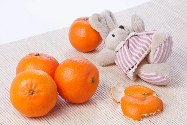 Happy toy rabbit rests near the pile of tangerines — Stock Photo, Image