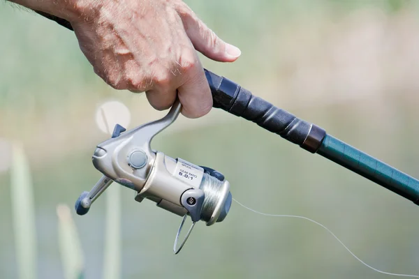 Pescador mano sosteniendo una caña de pescar — Foto de Stock