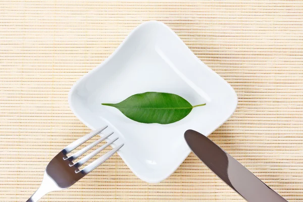 Green leaf on a plate as vegetarian diet - concept of healthy dieting