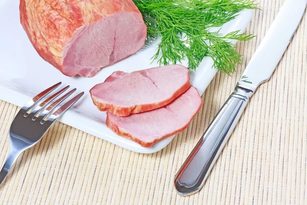 stock image Smoked ham and dill on plate with knife and fork