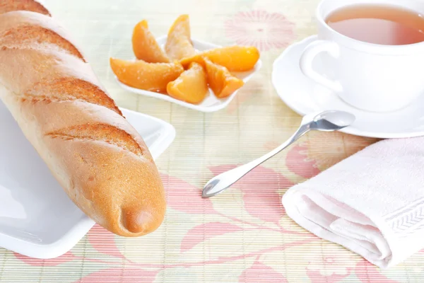 Baguette on plate, peach dessert and a cup of tea — Stock Photo, Image