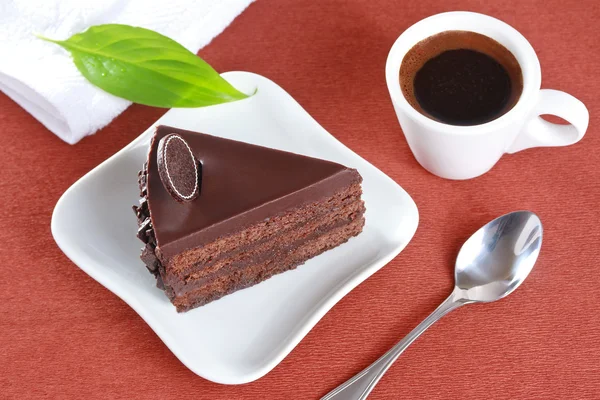 Pastel de chocolate y una taza de café sobre un fondo marrón — Foto de Stock