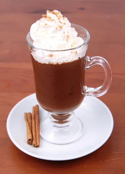 热巧克力和奶油和肉桂粉放在杯子里木背景上 — 图库照片