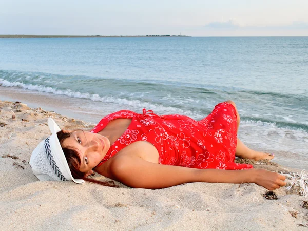 Kobieta w czerwonej sukience i kapelusz na plaży — Zdjęcie stockowe