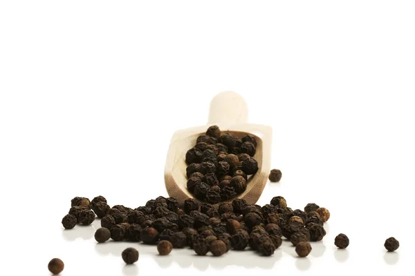 Stock image Black peppercorns from a small wooden shovel front