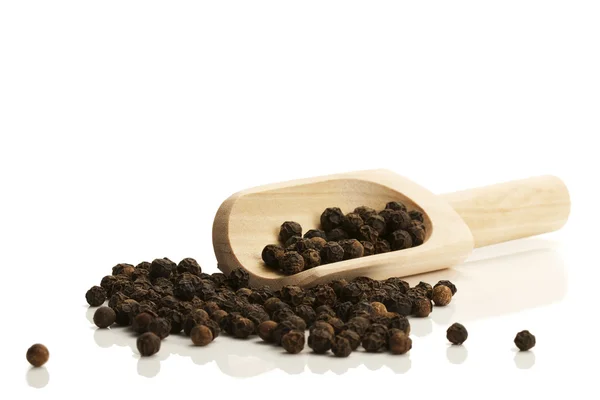 Черный перец с маленькой деревянной лопатой — стоковое фото