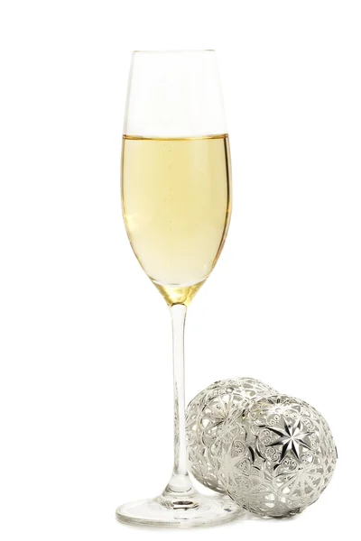 Sklenka šampaňského s dvěma kovové vánoční koule — Stock fotografie