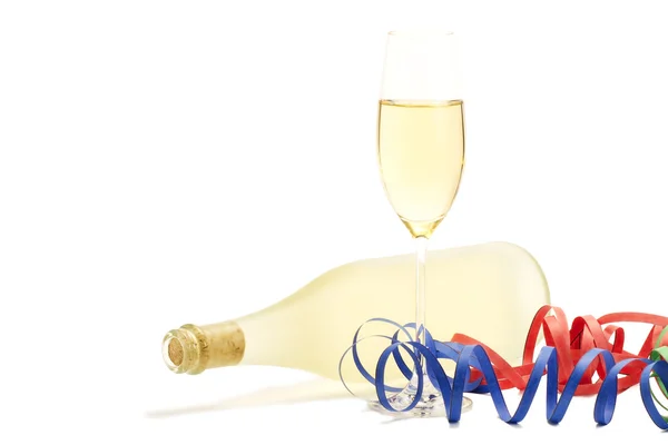 Glas met champagne met streamer tegenover een fles prosecco — Stockfoto