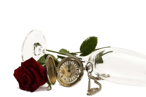Oude zakhorloge met een rode natte roos onder een leugenachtige champagne glas — Stockfoto