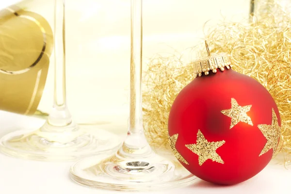 Närbild av en röd tråkig jul boll med champagne glas botten framme o — Stockfoto