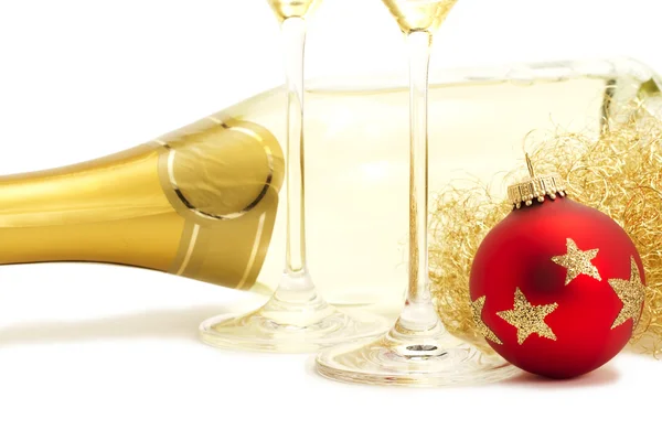 Red christmas ball in front of angels hair, two champagne glasses bottoms a — Stock Photo, Image