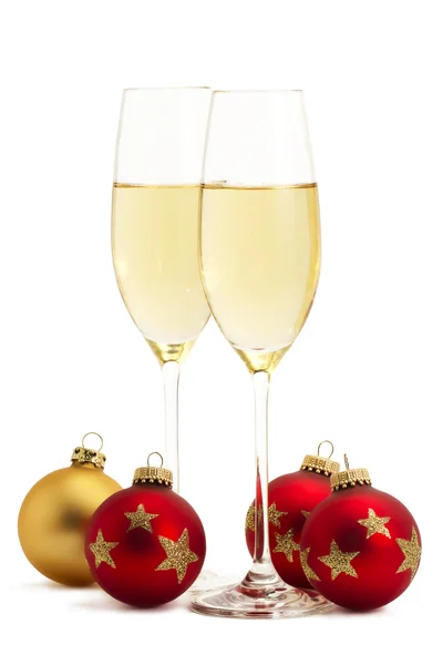 Twee glazen met champagne met een gouden en drie rode kerstballen — Stockfoto